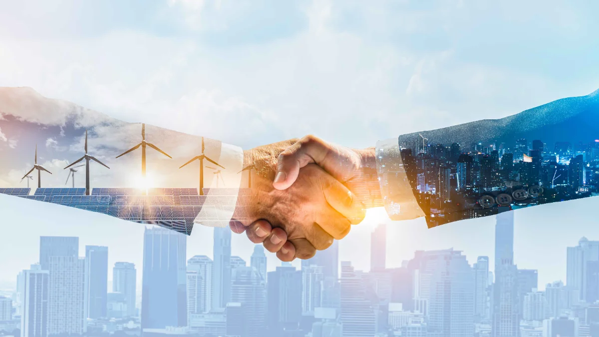Handshake over solar panels, wind turbines and a city skyline